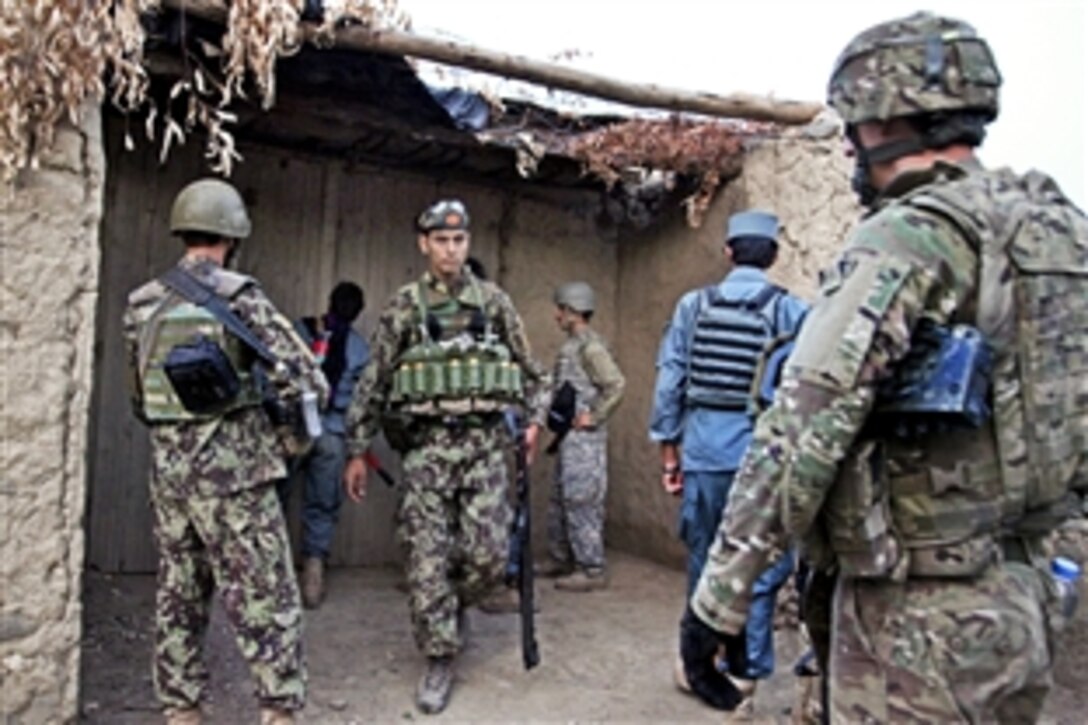 Afghan police officers join U.S. and Afghan soldiers as they prepare to enter a pump house to search for weapons caches in Karizownah in Afghanistan's Khost province, July 30, 2012. 