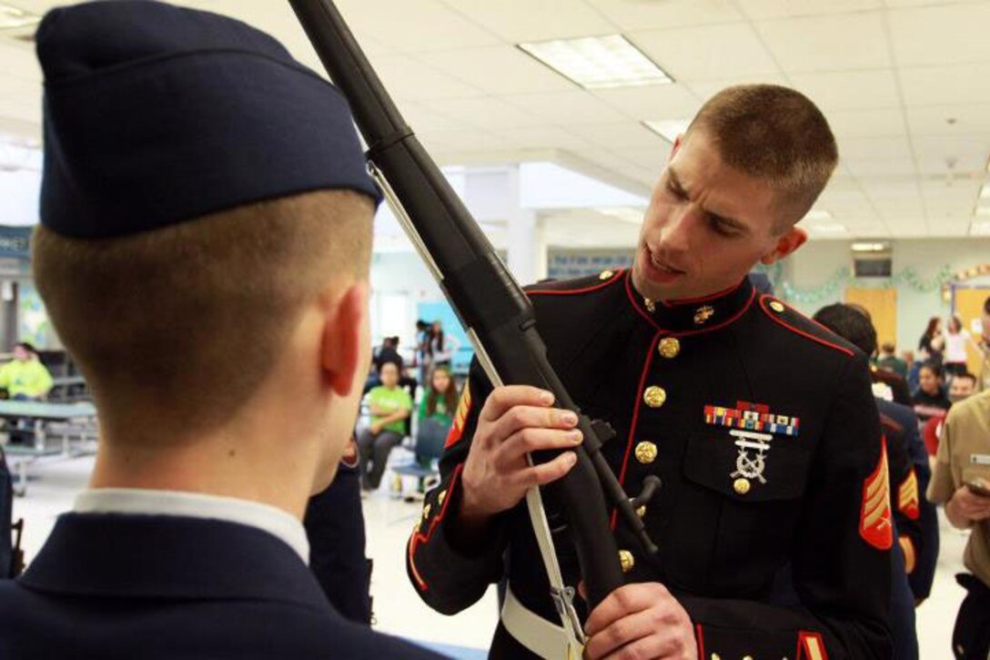 Sgt. Edward Gorsegner, a recruiter from Recruiting Substation Tacoma, Recruiting Station Seattle, inspects a cadet's replica Springfield 1903 rifle during a Junior Reserve Officers' Training Corps competition at Liberty High School in Renton, Wash., March 17