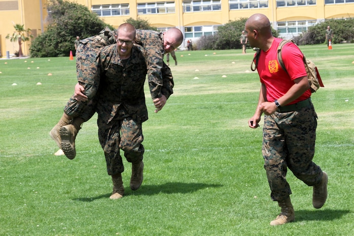 A recruit of Company B, 1st Recruit Training Battalion, fireman carries a fellow recruit during a Combat Fitness Test aboard Marine Corps Recruit Depot San Diego Aug. 9. The fireman carry is just one part of the CFT that also includes exercises such as pushups and a dummy grenade toss. Recruits were encouraged by their drill instructors to do the best they could in each section of the CFT.