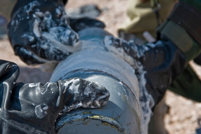 U.S. Air Force Airborne Explosive Ordnance Disposal Airmen assigned to the 820 the  RED HORSE patch a  simulated chemical round  during a training exercise Aug. 14, 2012, at Nellis Air Force Base, Nev. The EOD Airmen use a plaster of Paris bandage to seal two puncture holes in the training chemical round. The plaster helps contain the chemicals or substances inside the round. (U.S. Air Force photo by Airman 1st Class Daniel Hughes)