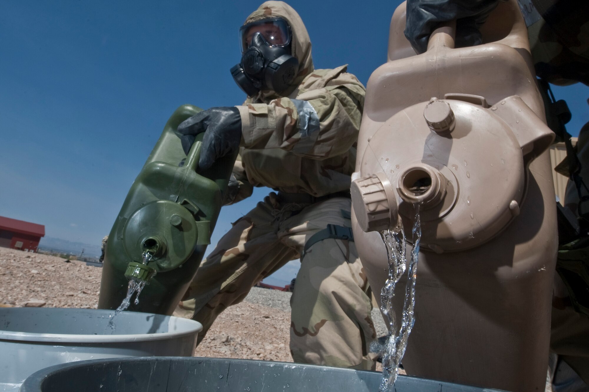 U.S. Air Force Airborne Explosive Ordnance Disposal Airmen assigned to the 820th RED HORSE pour decontamination liquids into a bucket during a training exercise Aug. 14, 2012, at Nellis Air Force Base, Nev. The liquids are used to decontaminate the Airmen that come into contact with chemicals or unknown substances. (U.S. Air Force photo by Airman 1st Class Daniel Hughes)
