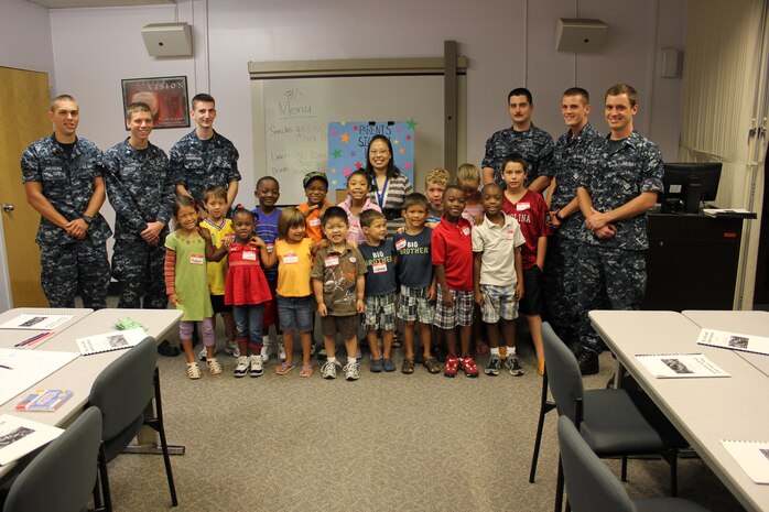 Navy volunteers and a group of campers pause during one of their workshops at the Fleet and Family Support Center Personal Financial Management and Life Skill Education summer camp. The annual camp was held Aug. 1 to 3 at the Joint Base Charleston – Weapons Station, S.C.  This year’s theme was FUNancial Summer Camp. More than 60 participants learned and explored the fields of entrepreneurship, finance, being wise consumers and making healthy life choices. This free educational camp was open to military children of all services. (Courtesy photo)