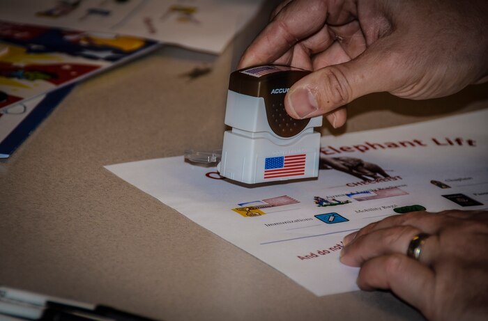 Master Sgt. Ricky Smith, 628th Force Support Squadron readiness noncommissioned officer-in-charge, stamps a checklist during the Children’s Deployment Camp, Aug. 14, at Joint Base Charleston – Air Base, S.C. Children had the opportunity to go through a deployment-processing line similar to what their parents have gone through in preparation for a deployment. (U.S. Air Force photo by Senior Airman Anthony Hyatt)