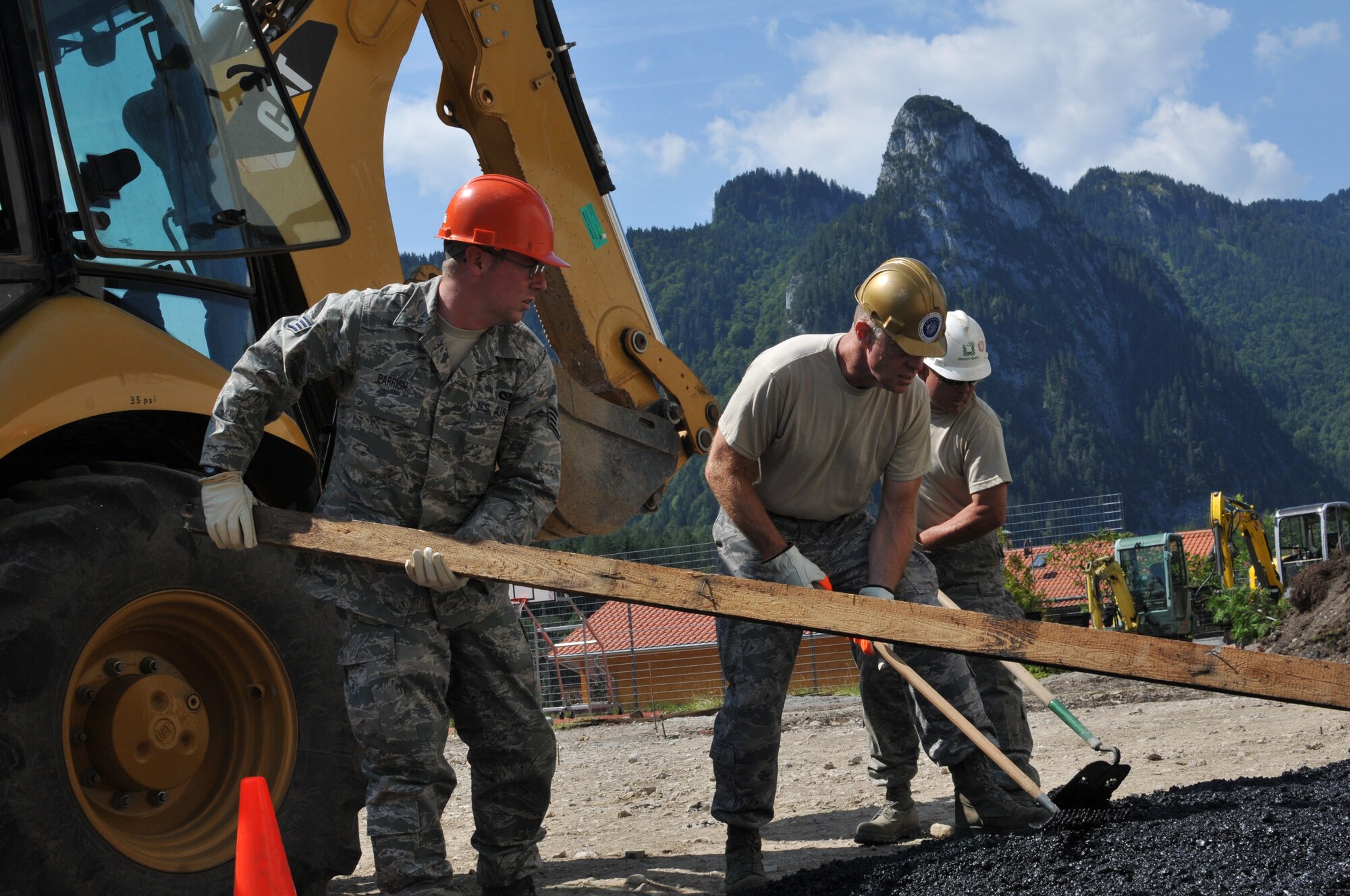 Members of the Wyoming Air National Guard's 153rd Civil Engineer Squadron Staff Sgt. Robert Parrish, Chief Master Sgt. Emery Edwards and Master Sgt. Andy Salyards smooth asphalt Aug. 13, 2012, at the NATO School recreation center, Oberammergau, Germany. Airmen from the 153rd CES are putting their skills to work as they conduct their annual training. (U.S. Air Force photo by Staff Sgt. Natalie Stanley)