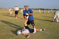 Elliott Ortiz, Joint Base San Antonio-Randolph High School coach, helps football player Jackso Kins stretch before early morning practice Aug. 13. The football team started summer practice at Randolph Texas, Aug 6. (U.S. Air Force photo by Rich McFadden) 