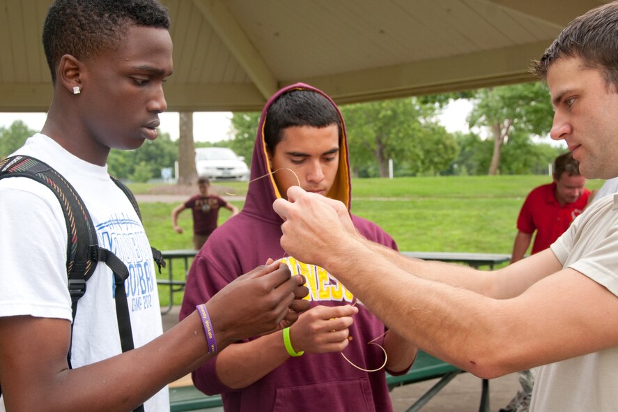 Staff Sgt. Scott Perlick, a Survival, Evasion, Resistance and Escape Specialist from the 934th Operational Support Squadron, Minneapolis, Minn. assists Air Force Junior Reserve Officers' Training Corps students from Woodbury and Park High Schools in making a simple snare using wire August 8, 2012. (U.S. Air Force Photo/Staff Sgt. Samantha Wagner)