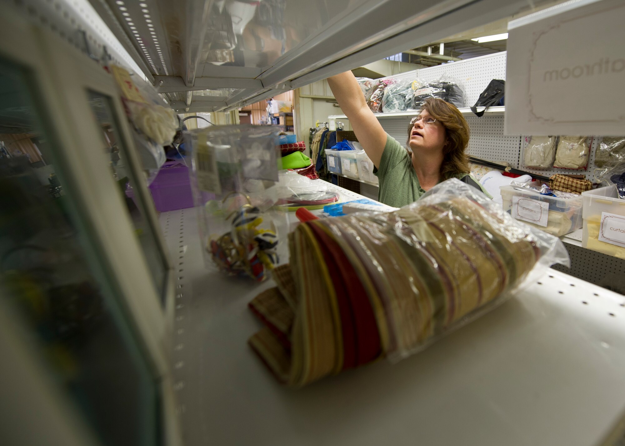 Lisa Johnson, wife of Col. Kenneth Johnson, 49th Operations Group commander, stocks a shelf at the Holloman Air Force Base, N.M., Thrift Store Aug. 14. The Thrift Store, located inside Building 232 on Second St. and Connecticut Ave., provides Team Holloman members a cheaper avenue of acquiring new and gently-used items at a fraction of the cost of the item’s retail value. The store, open Tuesdays and Thursdays from 10 a.m. to 2 p.m. and the first Saturday of every month starting in October, also offers consignment deals to anyone looking to sell their items. All profits from the Thrift Store go to helping multiple organizations on base and in the Alamogordo community. (U.S. Air Force photo by Senior Airman Siuta B. Ika/ Released)