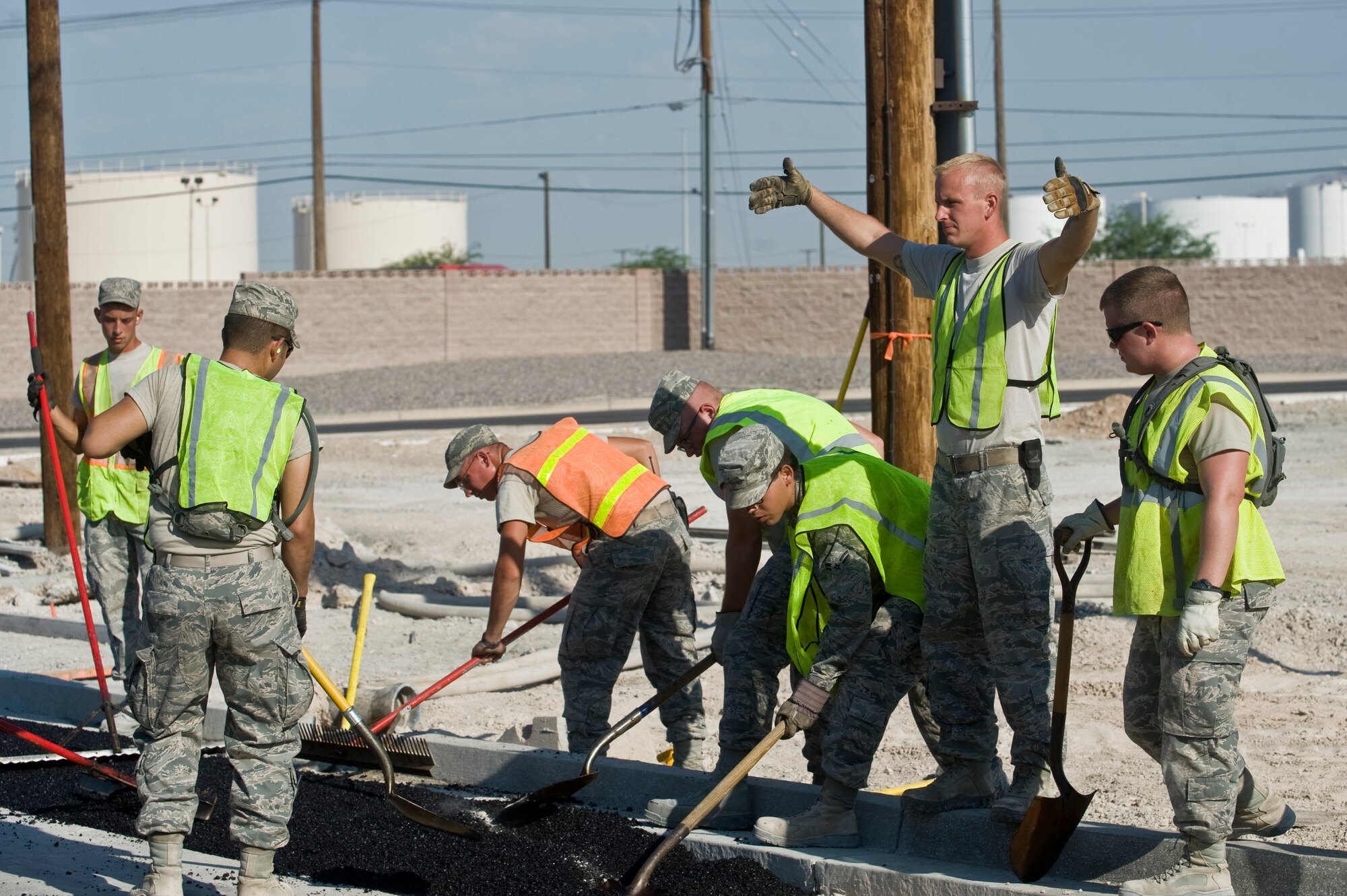 Senior Airman Nickolas Van Hoorebeck, 99th Civil Engineer Squadron heavy equipment and pavements journeyman, directs a front end loader full of asphalt to the next segment of sidewalk Aug. 15, 2012, at Nellis Air Force Base, Nev. Construction has been underway for more than three weeks and is on the second day of laying the foundation. (U.S. Air Force photo by Airman 1st Class Daniel Hughes)