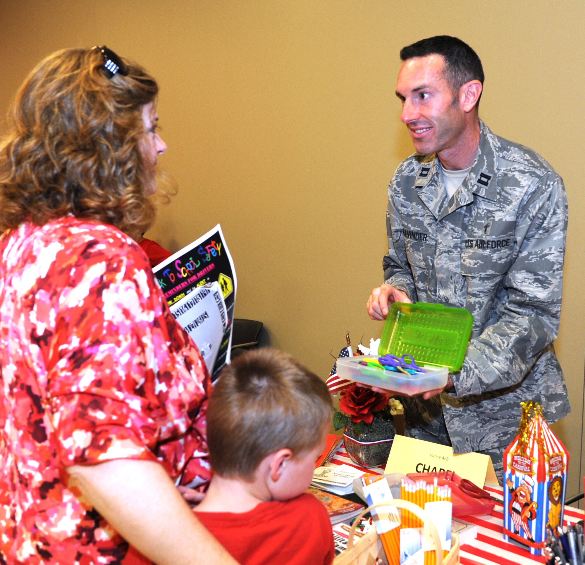 Chaplain (Capt.) Jon Bravinder offers school supplies to a mother and son during the Back to School Bash in the Armed Forces Reserve Center at Vance Air Force Base, Okla., Aug. 10.  More than 280 people attended the event hosted by the Airman & Family Readiness Center. (U.S. Air Force photo/ Airman 1st Class Frank Casciotta)