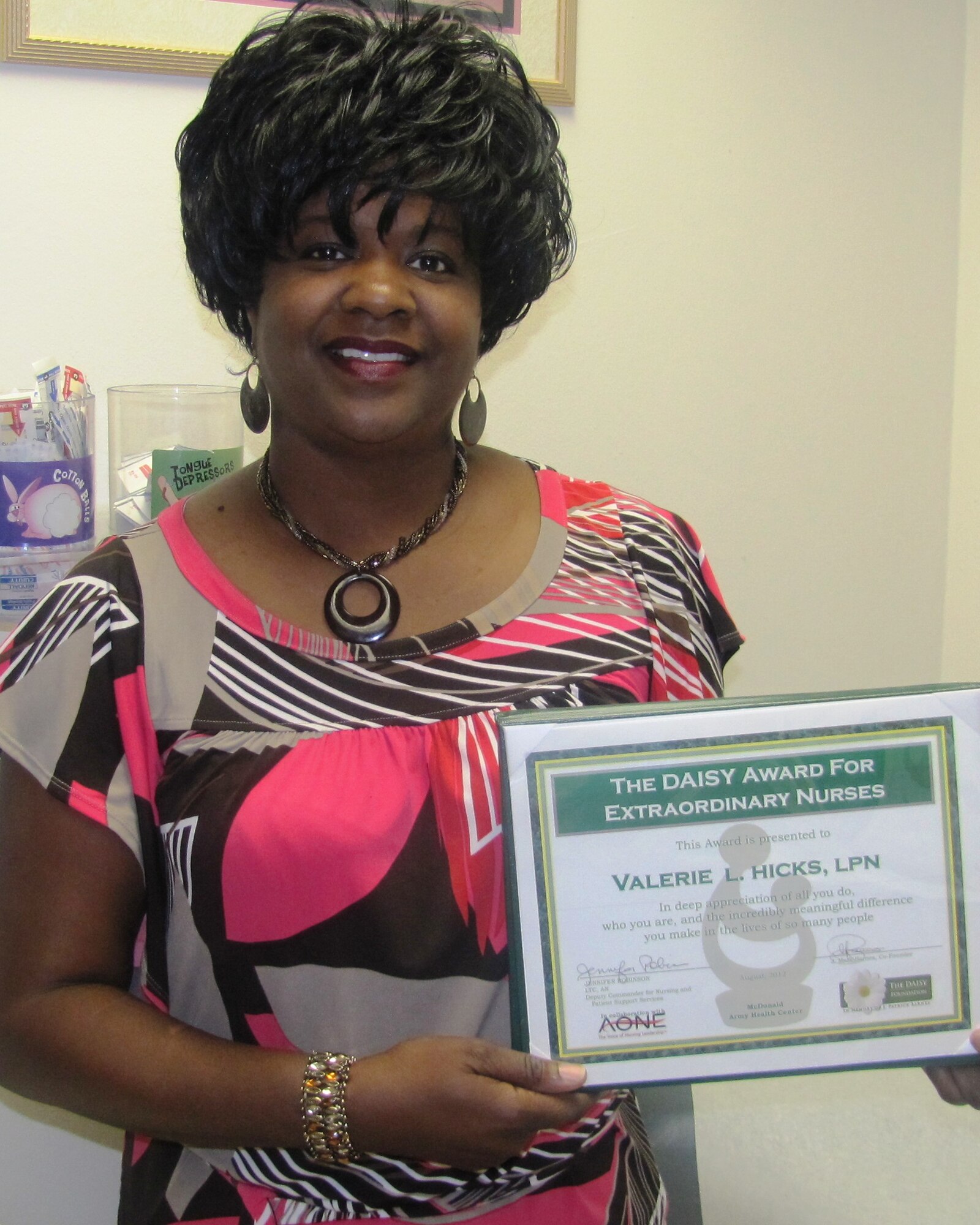 Valerie Hicks, McDonald Army Health Center Allergy/Immunization Clinic lead nurse, shows off her certificate for winnin the third quarter DAISY award. The The DAISY award, which stands for  “diseases attacking the immune system"  award is a nationwide program that rewards and celebrates the extraordinary clinical skill and compassionate care given by nurses each day. (Photo by Marlon Martin/Released)