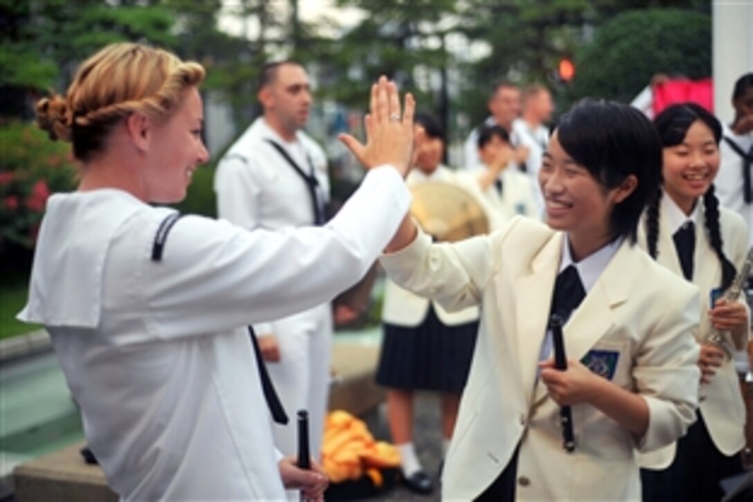 U.S. Navy Petty Officer 3rd Class Christa Vernon celebrates with a member of Seika Girls High School after their performance during a concert in the American consulate in Fukuoka, Hakata, Japan, Aug. 11, 2012. Vernon, a musician, is assigned to the U.S. 7th Fleet Band.