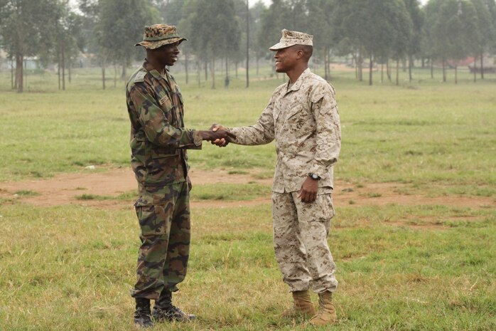 UGANDA - 1stLt. Herman Davis, the platoon commander of the engineer platoon from Battalion Landing Team 1st Battalion, 2nd Marine Regiment, 24th Marine Expeditionary Unit, shakes hands with a member of the Uganda People's Defense Force as they prepare for another day of training in Uganda.  Davis is serving as the team leader of a small group of Marines from the 24th MEU who went to Uganda to participate in a training mission as part of the African Union Mission in Somalia training Ugandan forces in basic marksmanship, small unit tactics, and engineering.  The 24th MEU is deployed with the Iwo Jima Amphibious Ready Group as a theater reserve and crisis response force in the U.S. Central Command and 5th Fleet areas of responsibility.