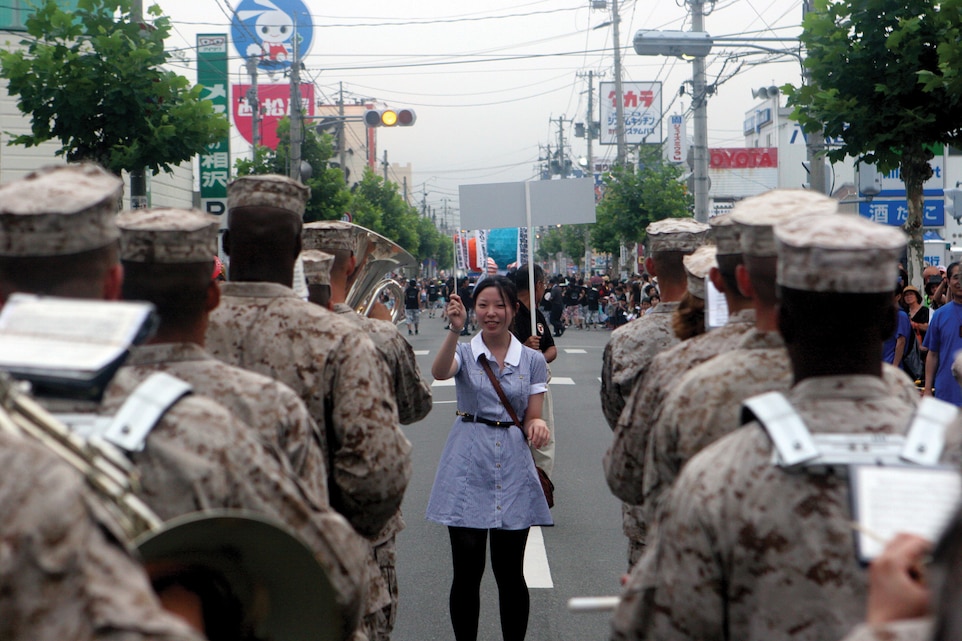 A spectator takes a turn conducting the III Marine Expeditionary Force Band during the 61st Kesennuma City Port Festival parade at Kesennuma City, Miyagi, Japan, Aug. 12.