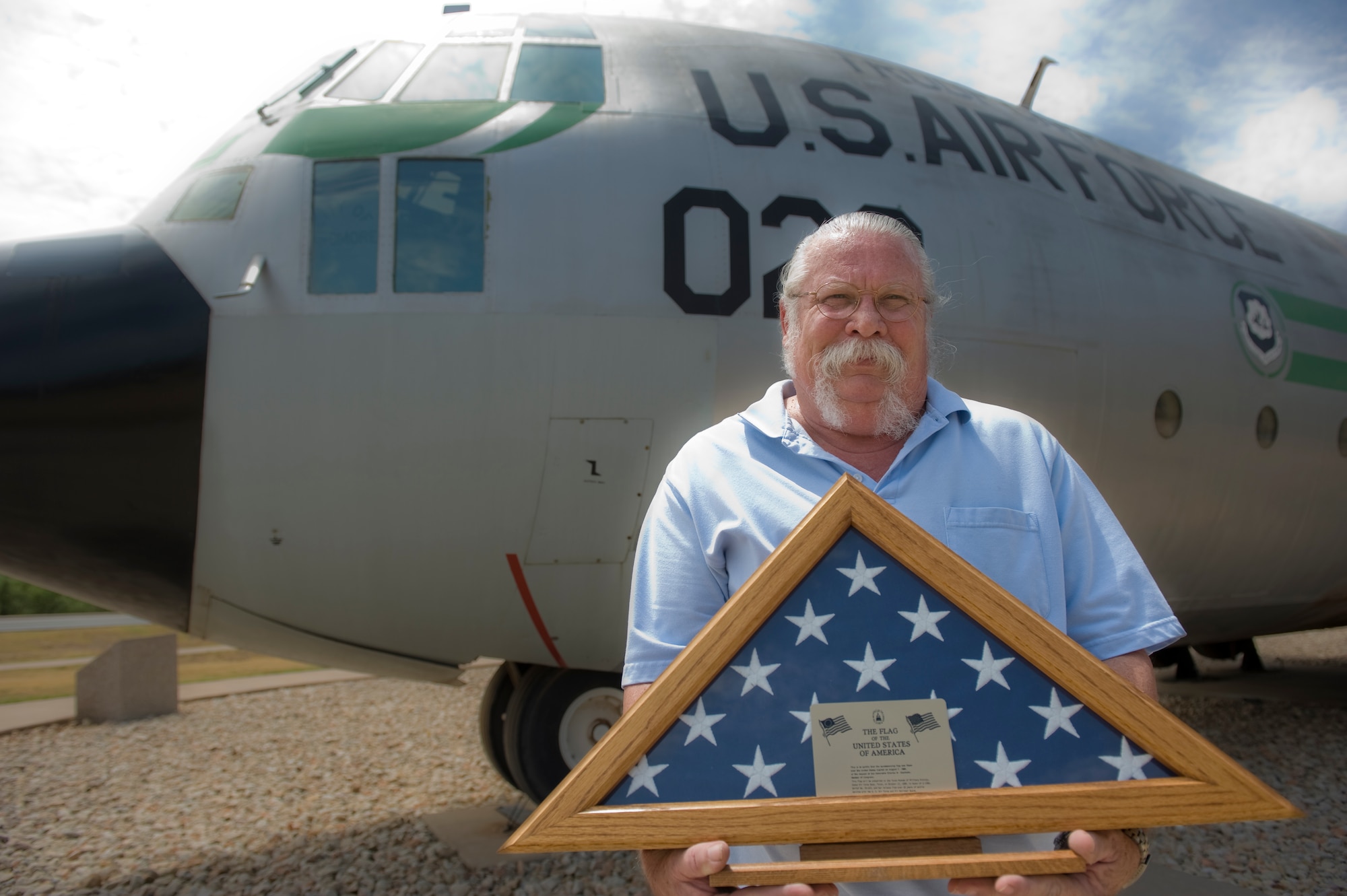 Richard “Doc” Warner, Linear Air Park curator, displays the American flag given to the first operational C-130 Aug. 15, 2012, at Dyess Air Force Base, Texas. The C-130, registration number 55-0023, was commissioned on Dec. 19, 1956, and completed 15,569.1 flying hours, or the equivalent of flying in the air for 648 and a half days during its 33 years of service before retiring at Dyess Air Force Base on Oct. 19, 1989. (U.S. Air Force photo by Airman 1st Class Jonathan Stefanko/ Released)