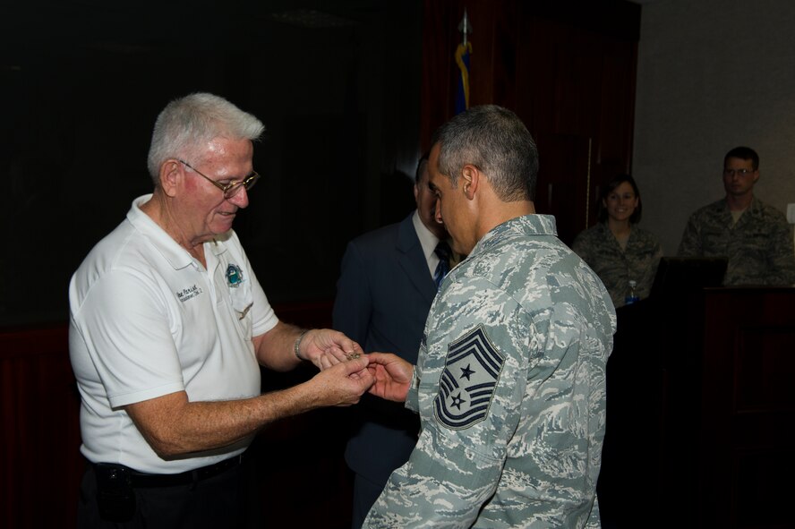 Dave Parisot, a commissioner of Okaloosa County, gives a pin to Chief Master Sgt. Ramon Colon-Lopez, command chief of 1st Special Operations Wing, during the presentation of the new sister county proclamation at wing headquarters on Hurlburt Field, Fla., Aug. 15, 2012. Okaloosa and Santa Rosa Counties have joined with Curry and Roosevelt counties near Cannon Air Force Base, N.M., as sister counties, commemorated with the proclamation. (U.S. Air Force photo/Airman 1st Class Christopher Williams)