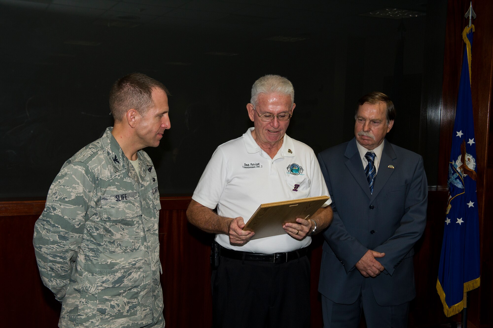 U.S. Air Force Col. Jim Slife, commander of 1st Special Operations Wing (left), Dave Parisot, a commissioner of Okaloosa County (middle) and Robert Cole, a commissioner of Santa Rosa County (right), look at the new sister county proclamation during a ceremony at wing headquarters on Hurlburt Field, Fla., Aug. 15, 2012. Okaloosa and Santa Rosa Counties are partnering up with Curry and Roosevelt Counties near Cannon Air Force Base, N.M., to bolster support to Air Force Special Operations Command Airmen and their families in both areas. (U.S. Air Force Photo/Airman 1st Class Christopher Williams)
