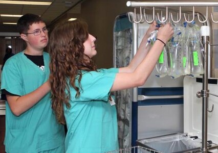 Volunteers Ryan Teich and Haley Richards label IV bags in the post-anesthesia care unit at the San Antonio Military Medical Center. The volunteer program brought 66 high school teens with more than 35 assigned supervisors throughout the medical center. (U.S. Army Photo by Kelly Schaefer, BAMC Public Affairs)