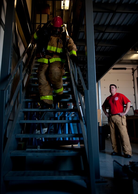 Airman 1st Class Bruce Lovett, 633rd Civil Engineer Squadron firefighter, practices the tower climb while being motivated by the 633rd CES Deputy Fire Chief, and team-mate, Senior Master Sgt. Matthew McQuaig, Aug. 13, 2012, at Langley Air Force Base, Va. The Firefighter Combat Challenge includes a five-story, 41-foot tower requiring participants to climb while their team-mates wait for the hand-off to start their own events. (U.S. Air Force photo by Senior Airman John Strong/Released)