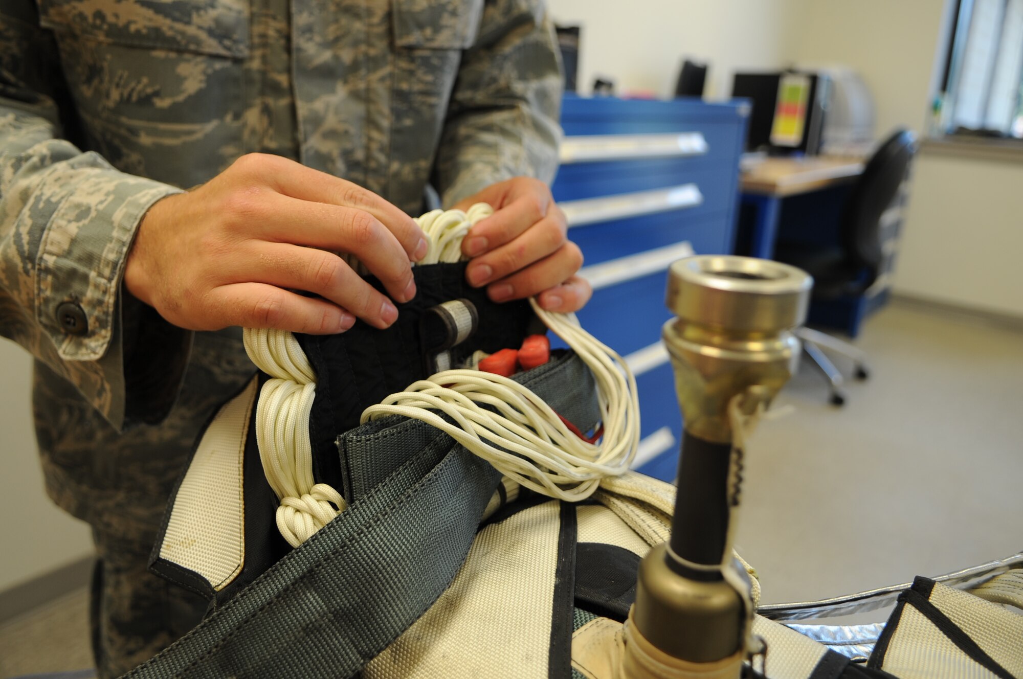 U.S. Air Force Senior Airman Colton Brown, 4th Operations Support Squadron aircrew flight equipment specialist, threads suspension lines into a parachute pack at the parachute shop on Seymour Johnson Air Force Base, N.C., Aug. 14, 2012. The lines must be threaded properly to ensure proper deployment of the chute following an ejection. (U.S. Air Force photo/Airman 1st Class Aubrey Robinson)