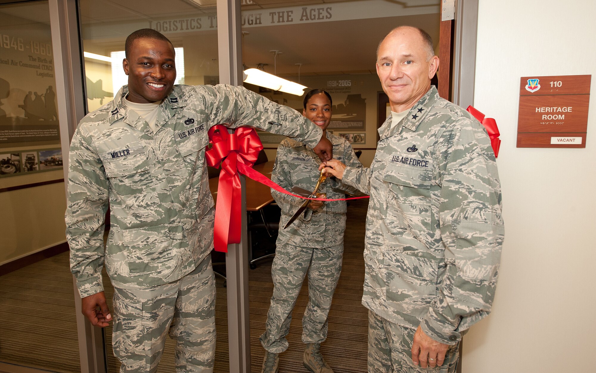 From right, U.S. Air Force Maj. Gen. Mark Atkinson, Air Combat Command Logistics director, U.S. Air Force Staff Sgt. Lasheena Johnson, ACC Logistics Readiness Division logistics detail manager, and U.S. Air Force Capt. Lyndel Miller, ACC Logistics Readiness Division command transportation functional manager, cut a ribbon commemorating the opening of their new heritage room at Langley Air Force Base, Va., Aug. 10, 2012. The room features photographs and illustrations showcasing Air Force logistics. (U.S. Air Force photo by Tech. Sgt. Barry Loo/Released)