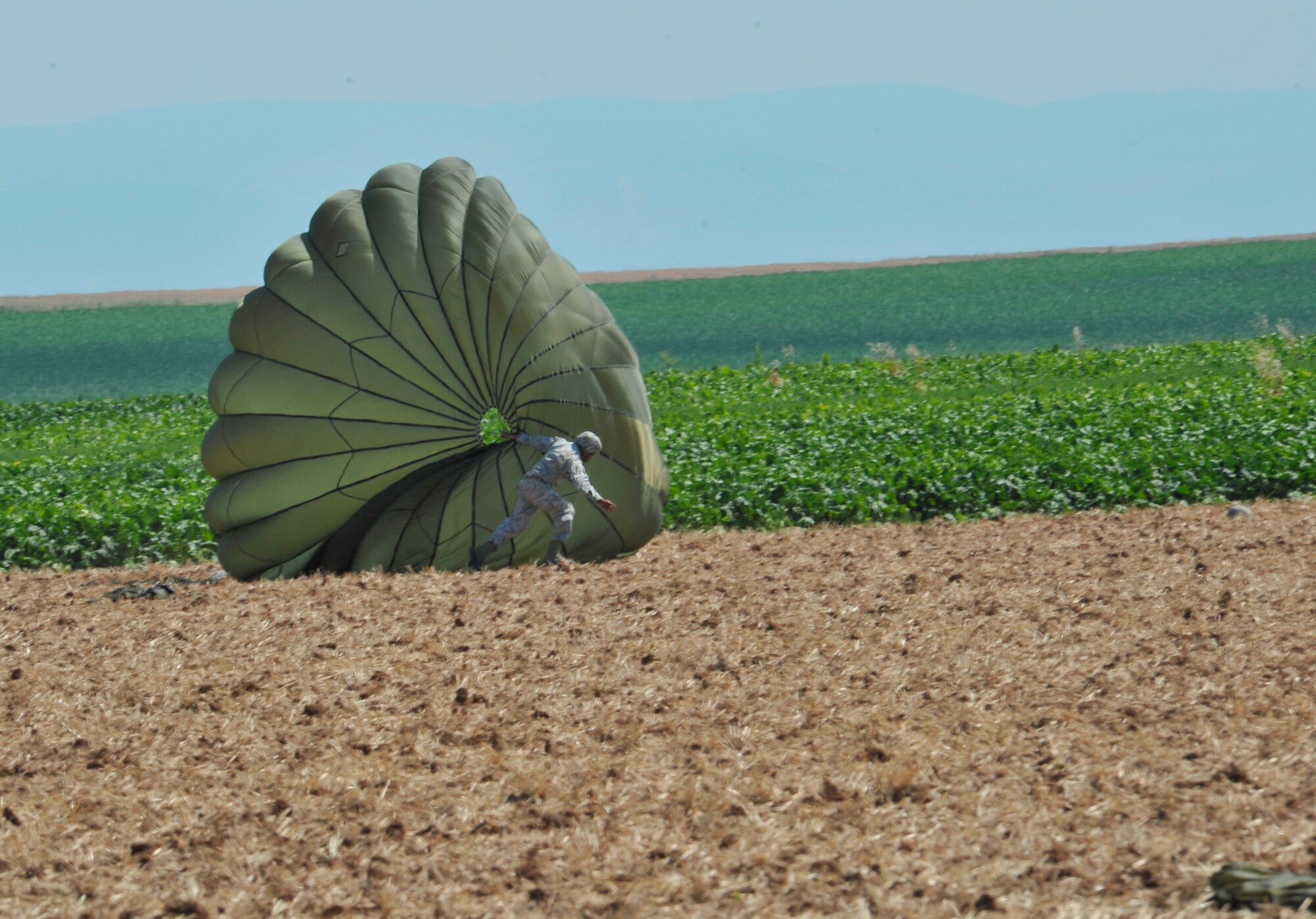 An Army paratrooper gathers his chute after landing on the drop zone Aug. 15, near Alzey Germany. Members of six NATO countries came together to trade jump tactics and techniques and got the opportunity to earn the other nation’s jump wings. (U.S. Air Force photo/Airman 1st Class Trevor Rhynes)