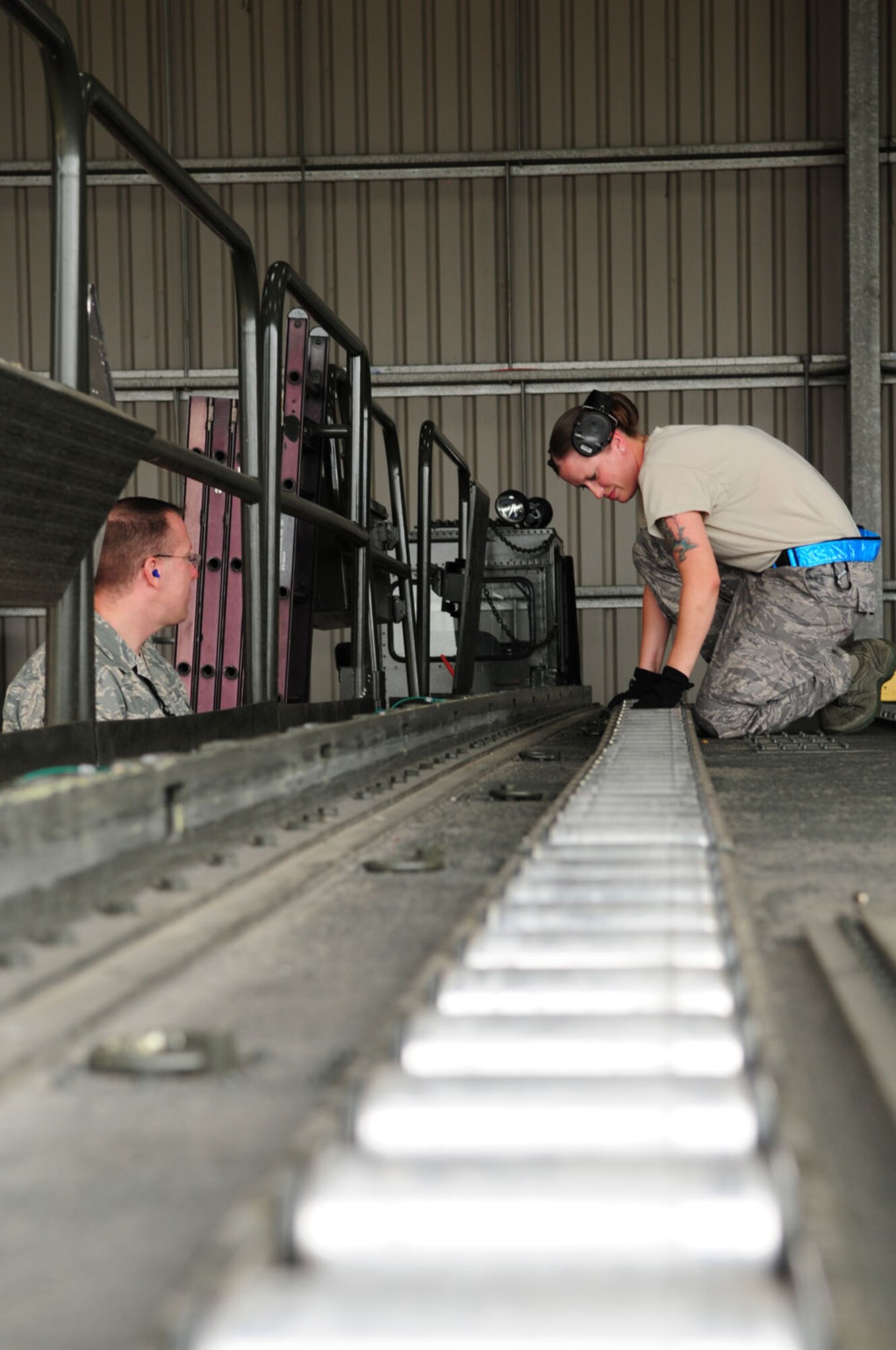 RAF MILDENHALL, England – Staff Sgt. Jamie Brede, 727th Air Mobility Squadron freight services supervisor, performs an inspection on the rollers and deck of a 60 K-loader as Master Sgt. Tracey Curtis, left, a Logistics Compliance Assessment Program inspector, looks on Aug. 15, 2012, at the 727th AMS Cargo Services area, RAF Mildenhall. The equipment inspection is performed twice a day, once every shift. Curtis, from Headquarters Air Mobility Command, Scott Air Force Base, Ill., evaluated military members and Ministry of Defence workers throughout air freight services, to ensure they are complying with Air Force policy. (U.S. Air Force photo/Karen Abeyasekere) 
