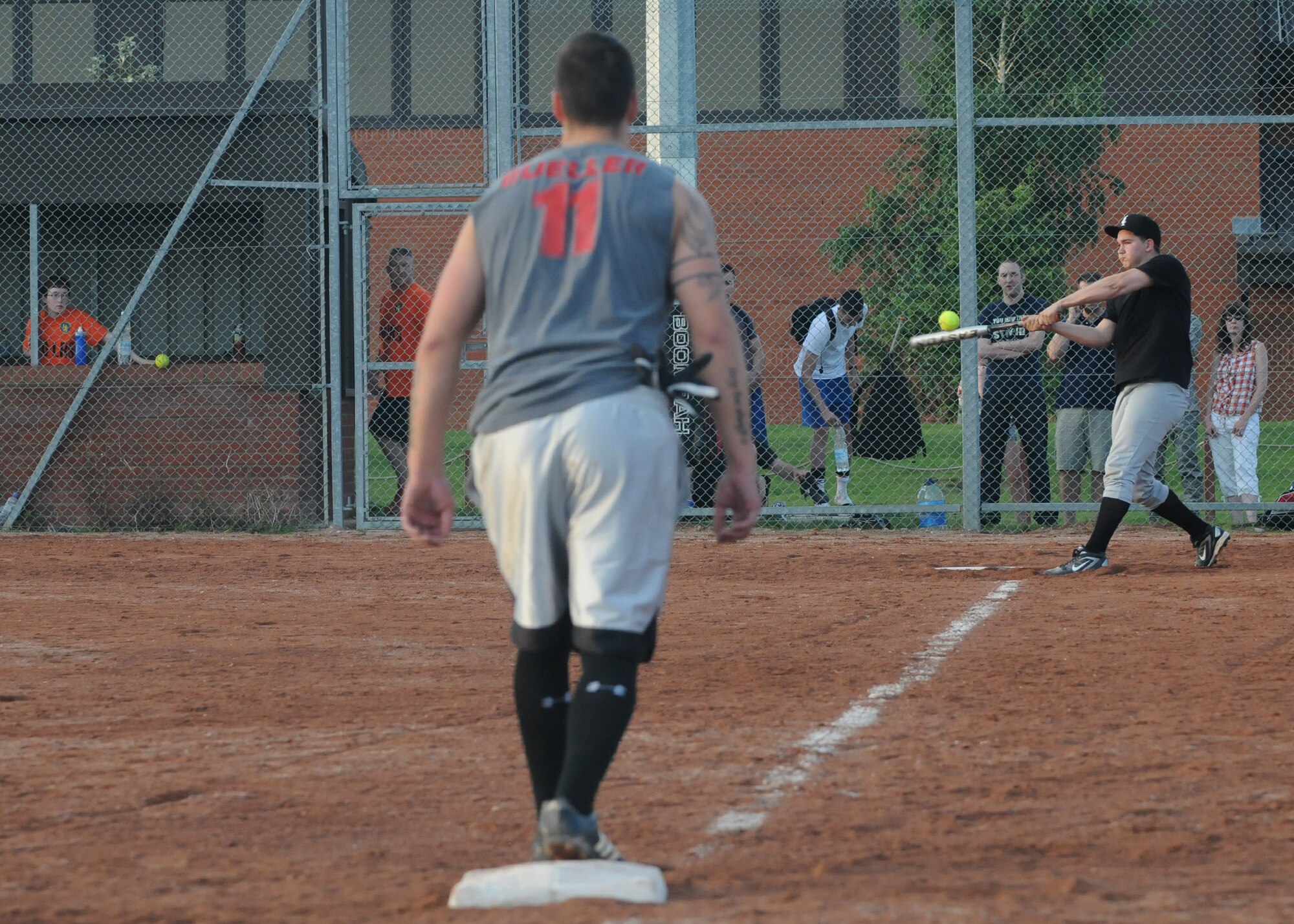 RAF MILDENHALL, England – David Kalinowski, 100th Logistics Readiness Squadron, hits the ball as Dakota Farris, 100th LRS, prepares to run home during the Team Mildenhall intramural softball championship Aug. 14, 2012. The 100th LRS defeated the 100th Security Forces Squadron 8 – 4 to claim the championship trophy. (U.S. Air Force photo by Tech. Neal X. Joiner)