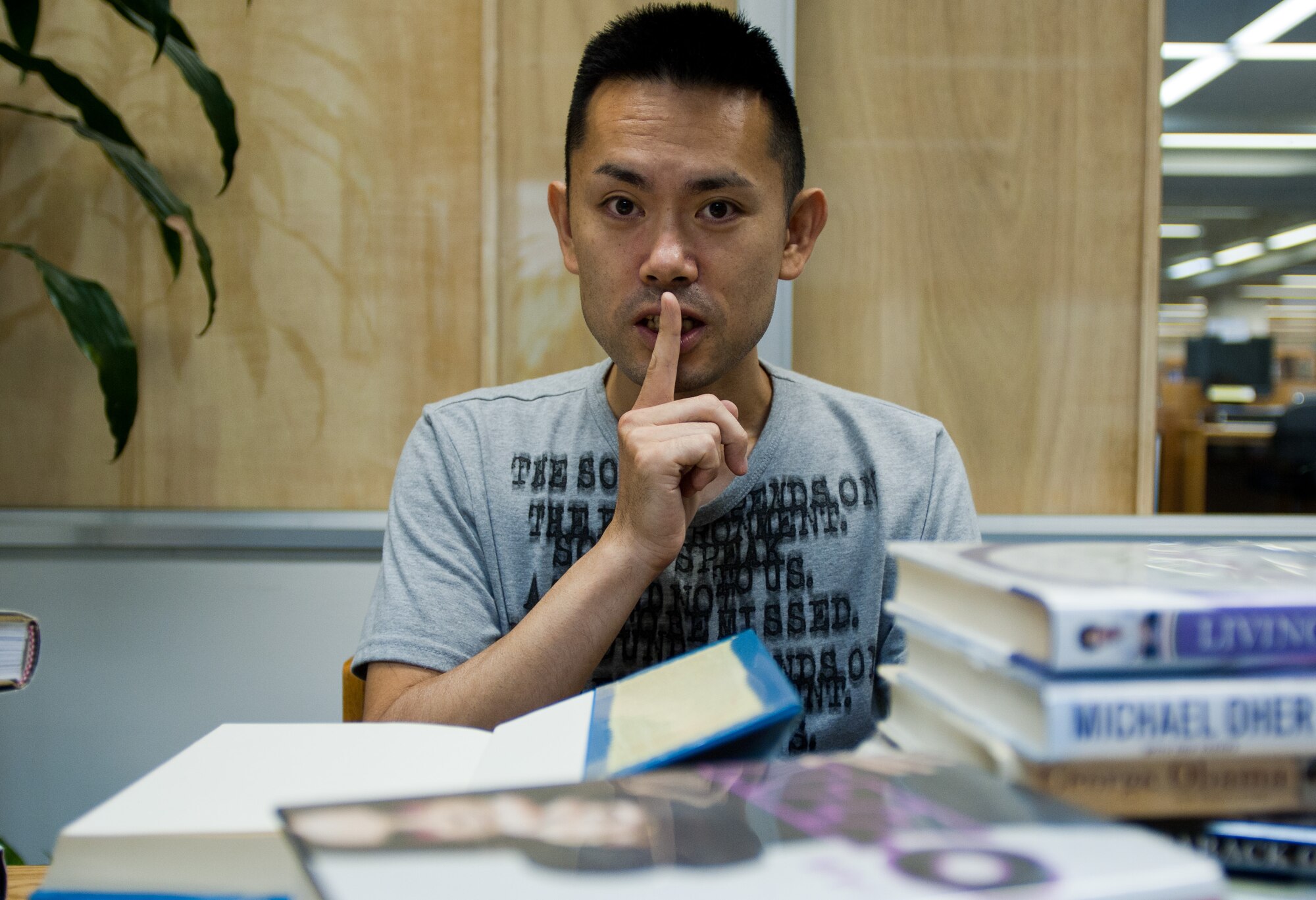 YOKOTA AIR BASE, Japan -- Jun Sekino, library technician, gestures for silence at the Base Library at Yokota Air Base, Japan, on Aug. 15, 2012. Cell phones must be set to silent mode at the library, and all phone calls must be taken outside. (U.S. Air Force photo by Airman 1st Class John D. Partlow)