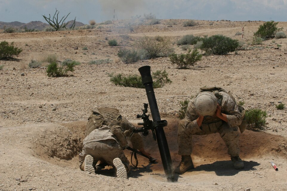 Lance Cpl. Daniel Williams and Cpl. Riley Dobbs, mortarmen with 1st Light Armored Reconnaissance Battalion Camp Pendleton, Calif., duck after firing a mortar round at a training site outside Yuma, Ariz., Aug. 13. Marines conducted combined arms attacks with air and ground assets to enhance proficiency controlling fixed wing and rotor wing aircraft during Scorpion Fire during a two-week training evolution that began Aug. 6.