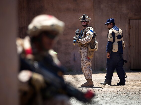 U.S. Marine Sgt. Daniel McCaughern (left), a squad leader with 1st Platoon, India Company, 3rd Battalion, 3rd Marine Regiment, and 24-year-old native of Deer Park, N.Y., looks back on his Marines during a non-lethal weapons training scenario in a simulated urban village on Marine Corps Training Area Bellows, Hawaii, Aug. 15, 2012. The training was part of a two-week test readiness review fielded by the Quantico, Va.-based Joint Non-Lethal Weapons Directorate and the Marine Corps Forces, Pacific Experimentation Center. The DoD Non-Lethal Weapons Program, headed by Commandant of the Marine Corps Gen. James Amos, trains operating forces on escalation of force options to minimize casualties and collateral damage, said Kelley Hughes, a directorate spokesperson.