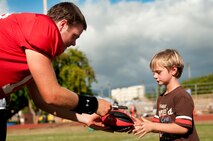 Sean Schroeder, University of Hawaii junior quarterback, signs an autograph for John, 7, son of Staff Sgt. Tommy Hazlewood, after an Aug. 16 Warriors practice at Earhart Field, Joint Base Pearl Harbor-Hickam, Hawaii. The team lived and worked out on Hickam Field from Aug. 13-17 due to the UH dormitories being cleaned and prepared for the start of the fall session. The Warriors are scheduled to be on the road for their opener Sept. 1, in Los Angeles, against the University of Southern California Trojans. Hazlewood is assigned to the 15th Medical Group, Hickam Field. (U.S. Air Force photo/Staff Sgt. Mike Meares)