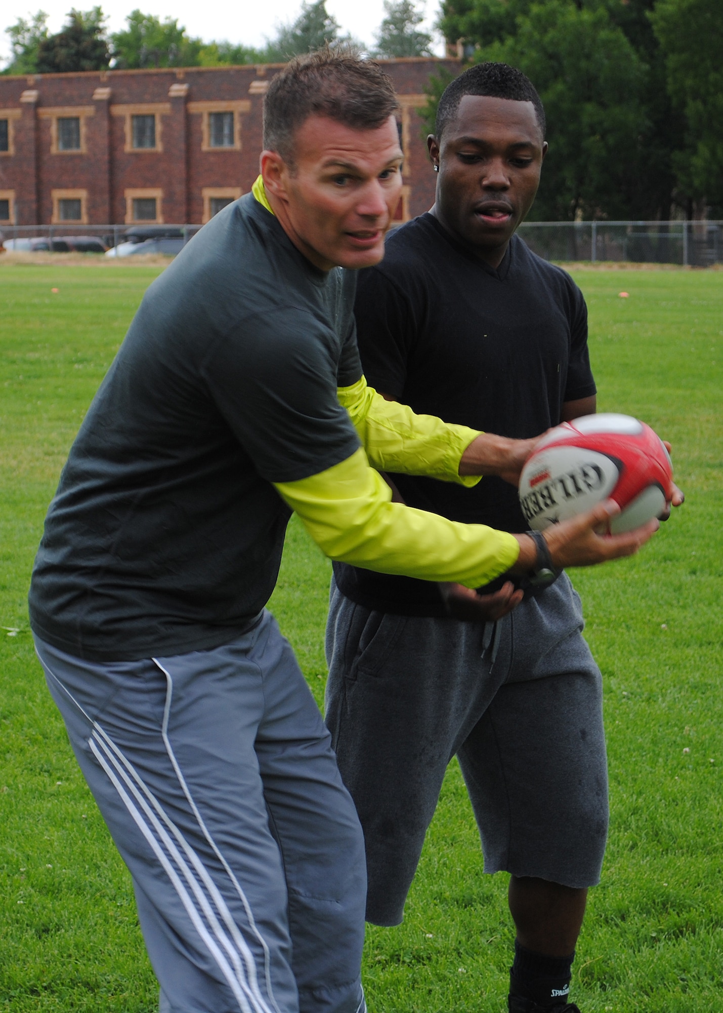Martin Fairhurst uses Airman 1st Class Jukens Estimon, 10th Missile Squadron missile chef, as his partner to show the rugby clinic how to do the next drill.  He and his wife, Staff Sgt. Danielle Fairhurst, 10th MS member, were two of the acting trainers during the rugby clinic on Aug. 15.  (U.S. Air Force photo/Airman 1st Class Cortney Paxton)
