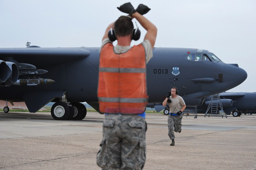 Airman 1st Class Logan Turner, 2nd Aircraft Maintenance Squadron crew chief, signals the aircrew in a B-52H Stratofortress to hold while Senior Airman Bryan Turner, 2 AMXS crew chief, runs away from the aircraft after pulling chalks on Barksdale Air Force Base, La., Aug. 15. Aircrews from Barksdale participated in Exercise Combat Hammer, which evaluated the employment of precision guided munitions to ensure the weapons are fully functional and mission capable. The exercise tested aircrews, munitions and maintenance Airmen on their performance. (U.S. Air Force photo/Airman 1st Class Micaiah Anthony)(RELEASED)