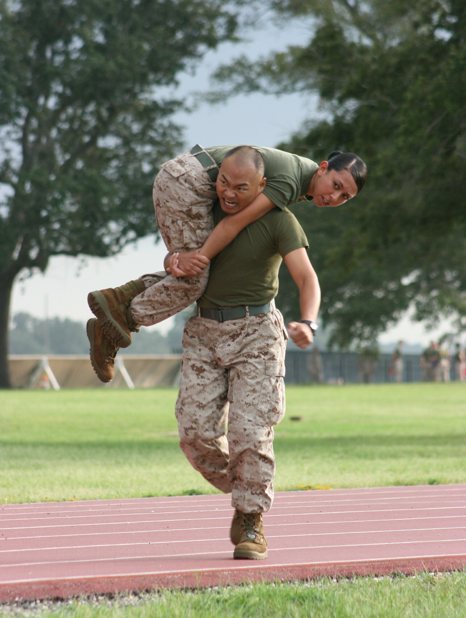 Keesler Marine Corps Detachment members, Lance Cpl. Kaechung Hou carries Lance Cpl. Jessica Ramos in the 400 meter fireman’s carry event of the MARDET Field Meet Aug. 3, 2012, at the Triangle track, Keesler Air Force Base, Miss.  Lance Cpls. Hou and Ramos are students in the General Purpose Calibration and Maintenance School at the Center for Naval Aviation Technical Training Unit on Keesler Air Force Base.  (U.S. Marine Corps photo by Marine Staff Sgt. Christopher Lambert)