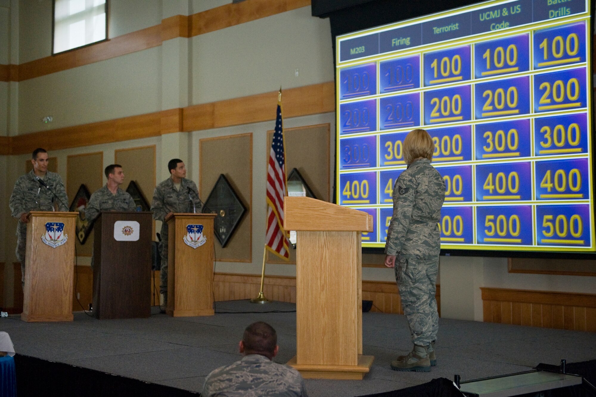 Staff Sgt. Paula Remetta, 341st Security Forces Squadron member (right), reads the next jeopardy question to Airman 1st Class Daniel Reshef, 741st Missile Security Forces Squadron security escort team leader, Senior Airman Matthew Rausch, 341st Security Forces Squadron member, and Airman 1st Class Alexandre Rogan, 341st SFS member, during the 341st SFS Game Show Challenge at the Grizzly Bend on Aug. 10.  Reshef took home the title of the first ever game show with a total of 19.300 points.  (U.S. Air Force photo/Beau Wade)