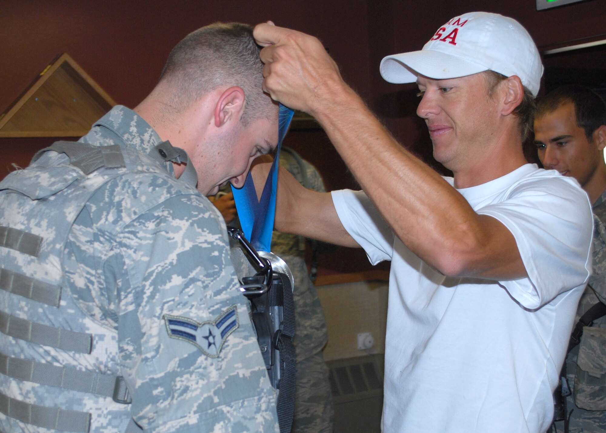 Todd Lodwick, five-time Olympian, puts his Olympic silver team medal around Airman 1st Class Korey Todd’s neck to show him how heavy it is and for a photo op.  Lodwick has shared his silver medal with more than 10,000 troops around the world.  (U.S. Air Force photo/Airman 1st Class Cortney Paxton)