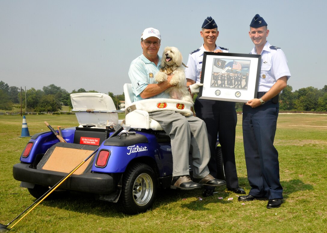 Maj. Gen. Gerard Caron, 79th Medical Wing commander, and Col. William Knight, 11th Wing/Joint Base Andrews commander, present Dennis Walters, Andrews Leadership Series guest speaker, a commemoration gift after his performance at the Club at Andrews Aug. 17, 2012.  Walters, who is paralyzed from the waist down;  his dog, Bucky;  and assistant, Asher Grogg, tour the nation as "The Dennis Walters Golf Show." Their show encourages viewers continually pursue their dreams despite life’s challenges.  (U.S. Air Force Photo/Senior Airman Lindsey A. Porter)