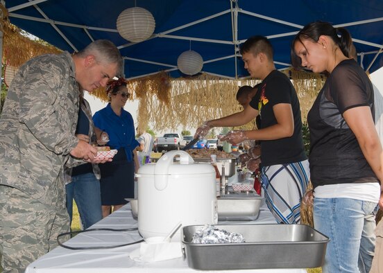 Airman 1st Class Eric Garrison, 341st Communications Squadron client support technician, serves food to Col. Mark Schuler, 341st Operations Group commander, at the Asian Pacific heritage booth, as Senior Airman Michelle Wilson, 341st Security Support Squadron member, looks on.  (U.S. Air Force photo/Beau Wade)