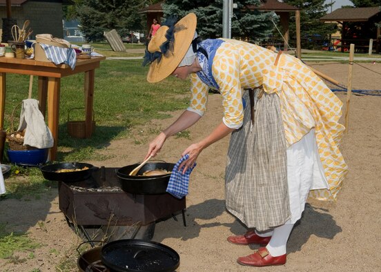 Sarah Nicci cooks pork with apple and onions over a fire pit as part of the women's history booth during the Multicultural Fair.  She also cooked apple fritters and macaroni and cheese the same way people did in the early 18th century.  (U.S. Air Force photo/Beau Wade)