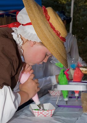 Arial Martin, 11, dressed up as historical figure Betsy Ross, squeezes frosting onto a cookie during the Multicultural Fair on Aug. 8.  (U.S. Air Force photo/Beau Wade)