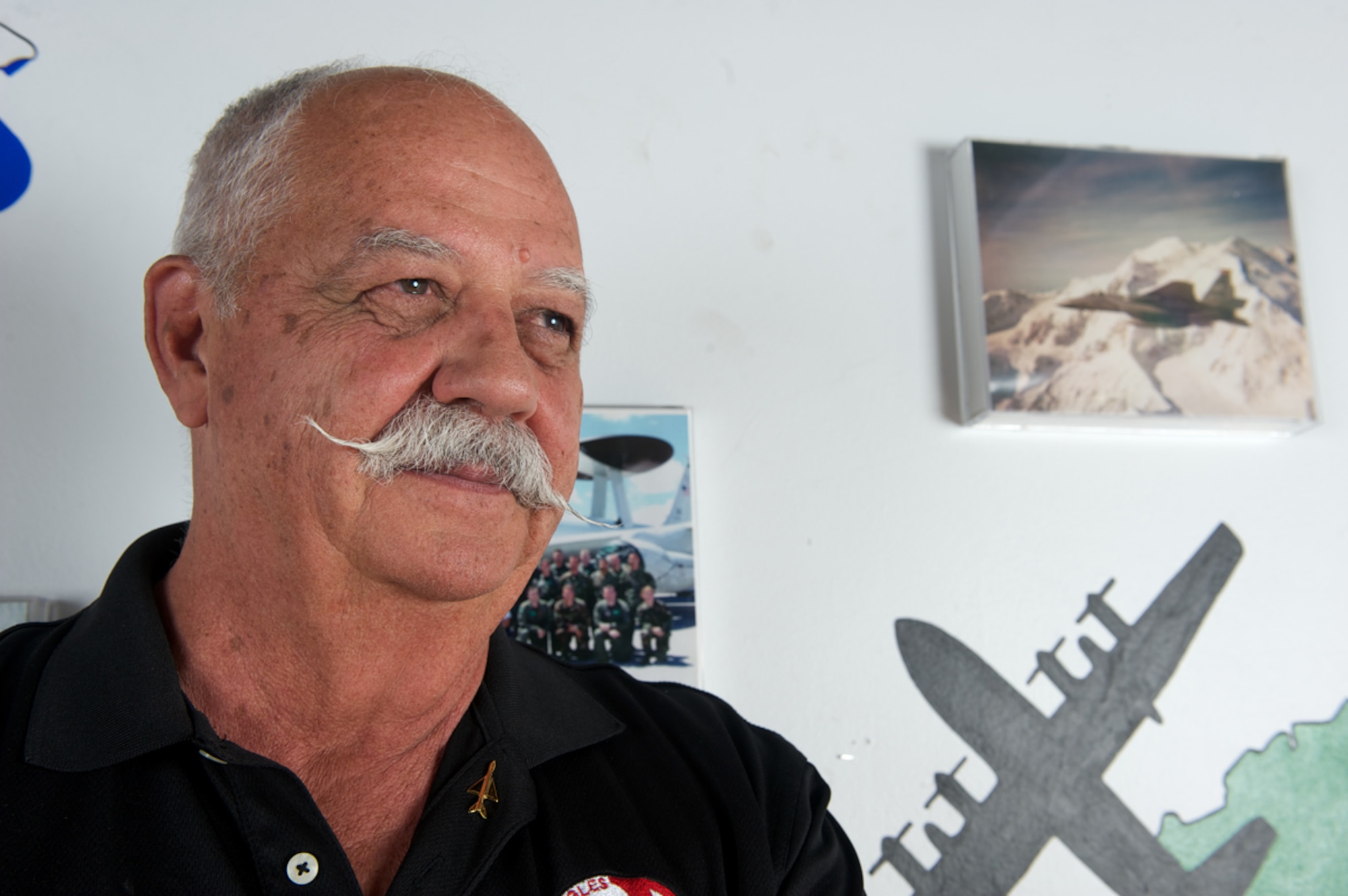 Retired Air Force Col. Gaillard Peck Jr., former 4477th Test and Evaluation Squadron commander, poses by a 3rd Wing heritage wall Aug. 10 at the Arctic Warrior Event Center. Peck wears a MiG-21 pin, which was the most common type operated by the squadron. (U.S. Air Force photo/David Bedard)