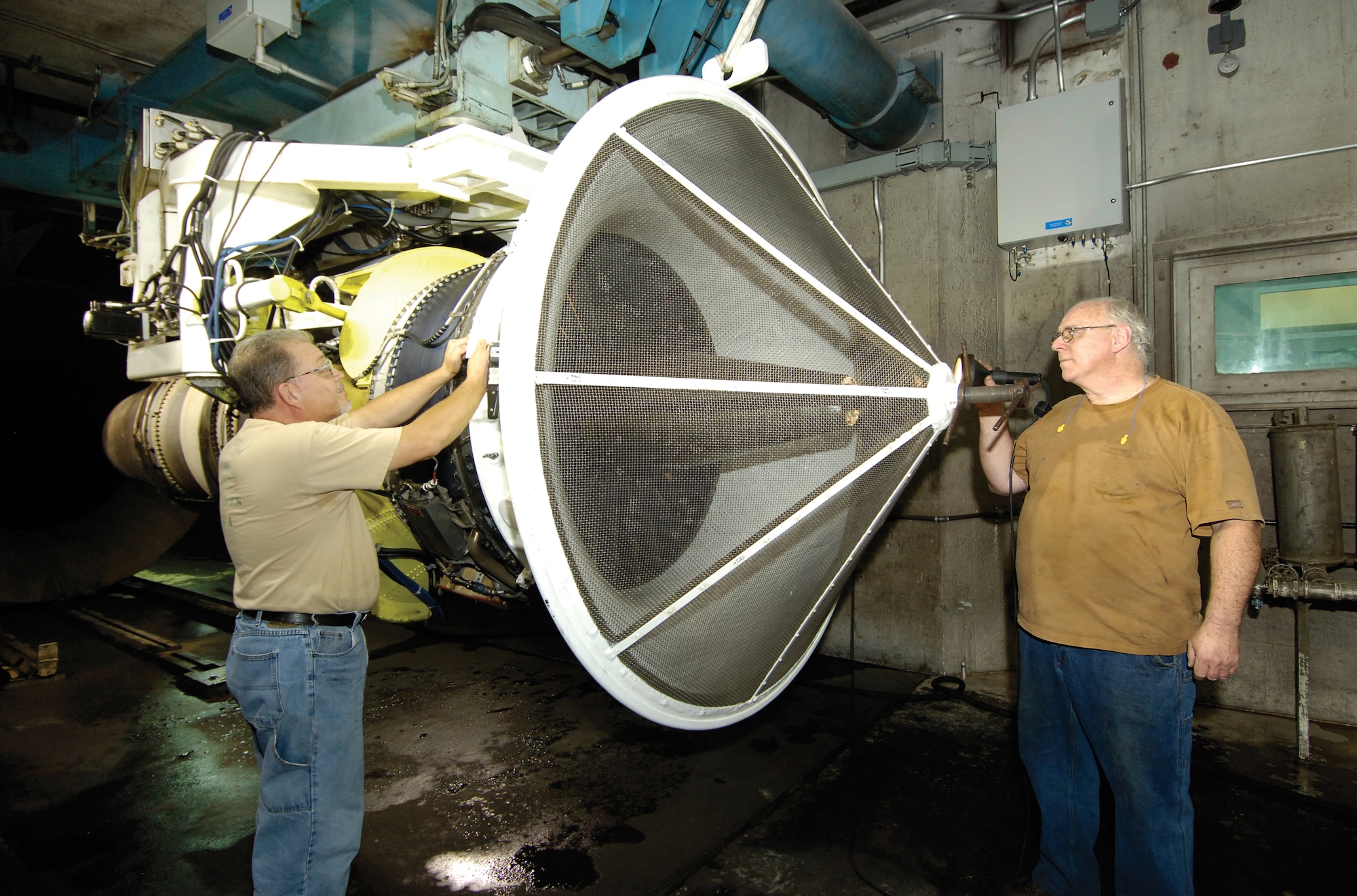 Engine test cell operator Mark Young, left, and inspector Bob Fischer check a TF33/P103 engine of a B-52H in Test Cell 8, Bldg. 3703.  The cell is identical to a nearby unused cell of the 547th Propulsion Maintenance Group’s Engine Test and Verification where an accidental release of oxygen-depleting fire suppressant sent workers clearing the building and emergency personnel responding to the alarm. (Air Force photo by Margo Wright)