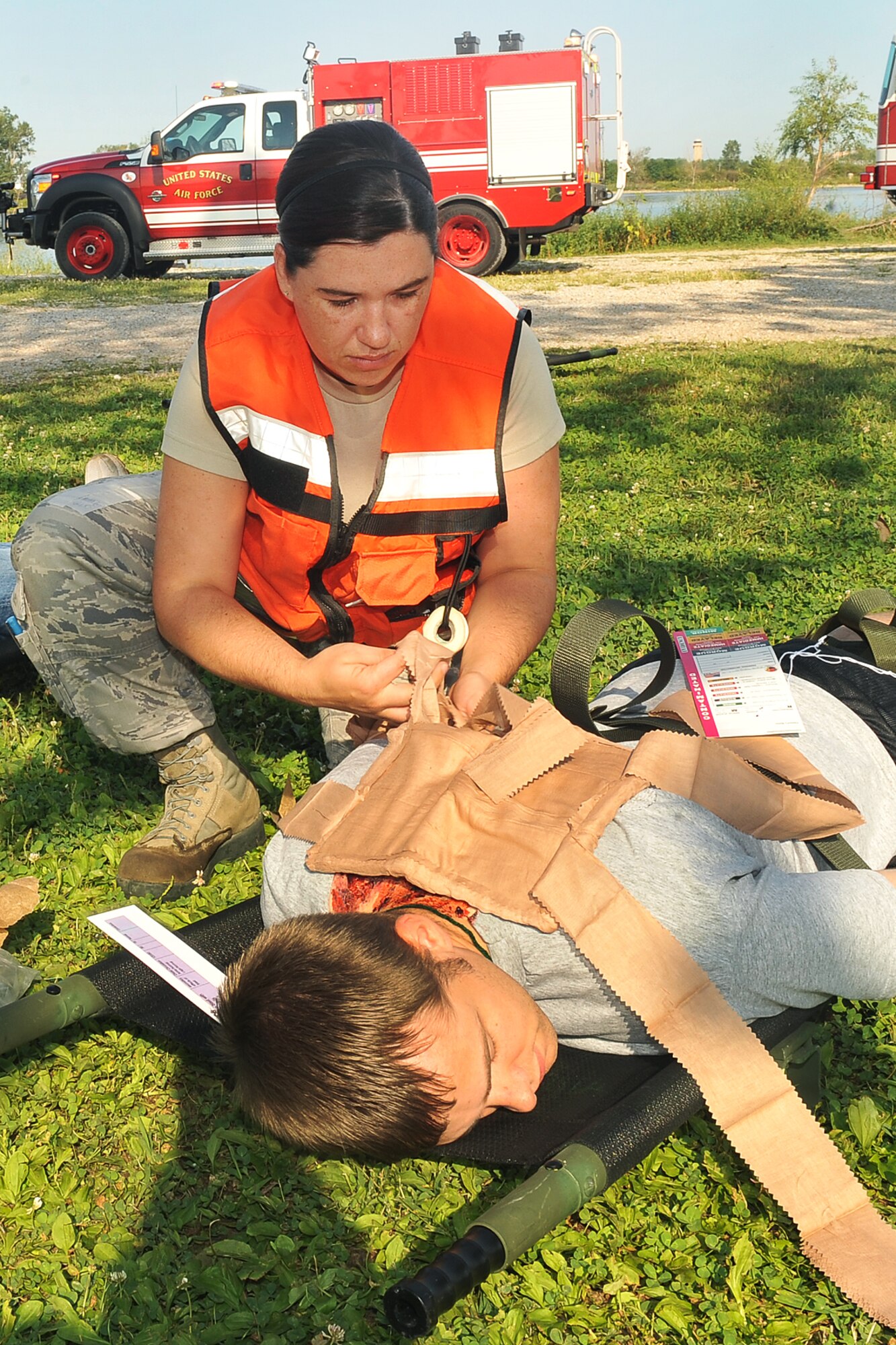 U.S. Air Force Staff Sgt. Amanda Ramsey, 1st Air Command Control Squadron, applies a bandage to the back wound of a mock causality during a major accident response exercise on Offutt AFB, Neb., Aug. 11. Airmen with the 55th Medical Group worked with medical professionals from the surrounding Omaha metro area during this annual exercise with a simulated aircraft accident in preparation for the Defenders of Freedom Open House and Air Show hosted here. (U.S. Air Force photo by Charles Haymond/Released)
