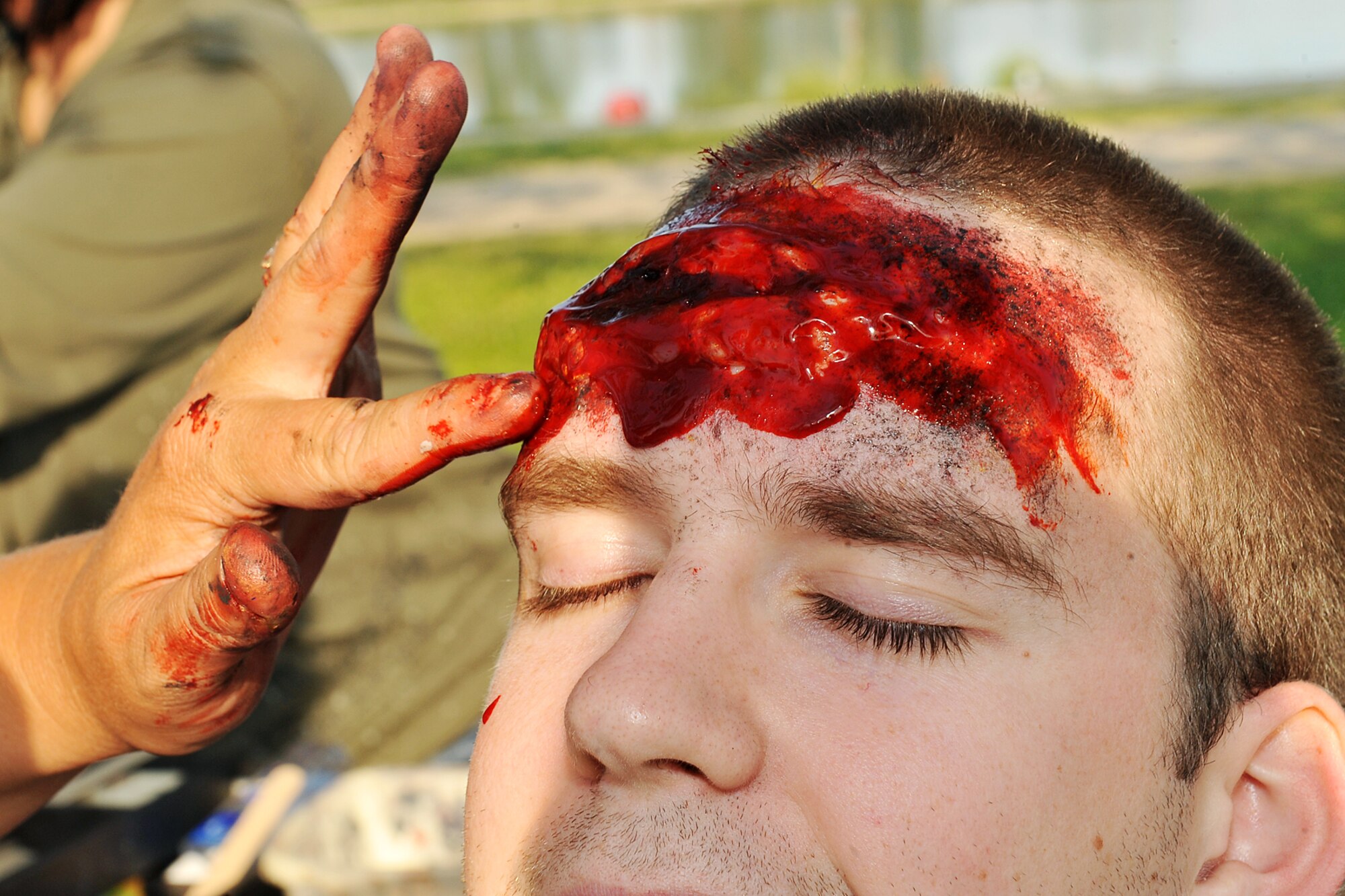 U.S. Air Force Staff Sgt. Lisa Barkley, 55th Medical Support Squadron, applies a fake head wound to U.S. Air Force Airmen 1st Class Nichols Benson, 55th Strategic Communications Squadron, during a major accident exercise on Offutt AFB, Neb., Aug. 11. Several agencies from the surrounding Omaha metro area participate in this exercise to practice the emergency response necessary for a large scale medical incident. (U.S. Air Force photo by Charles Haymond/Released)