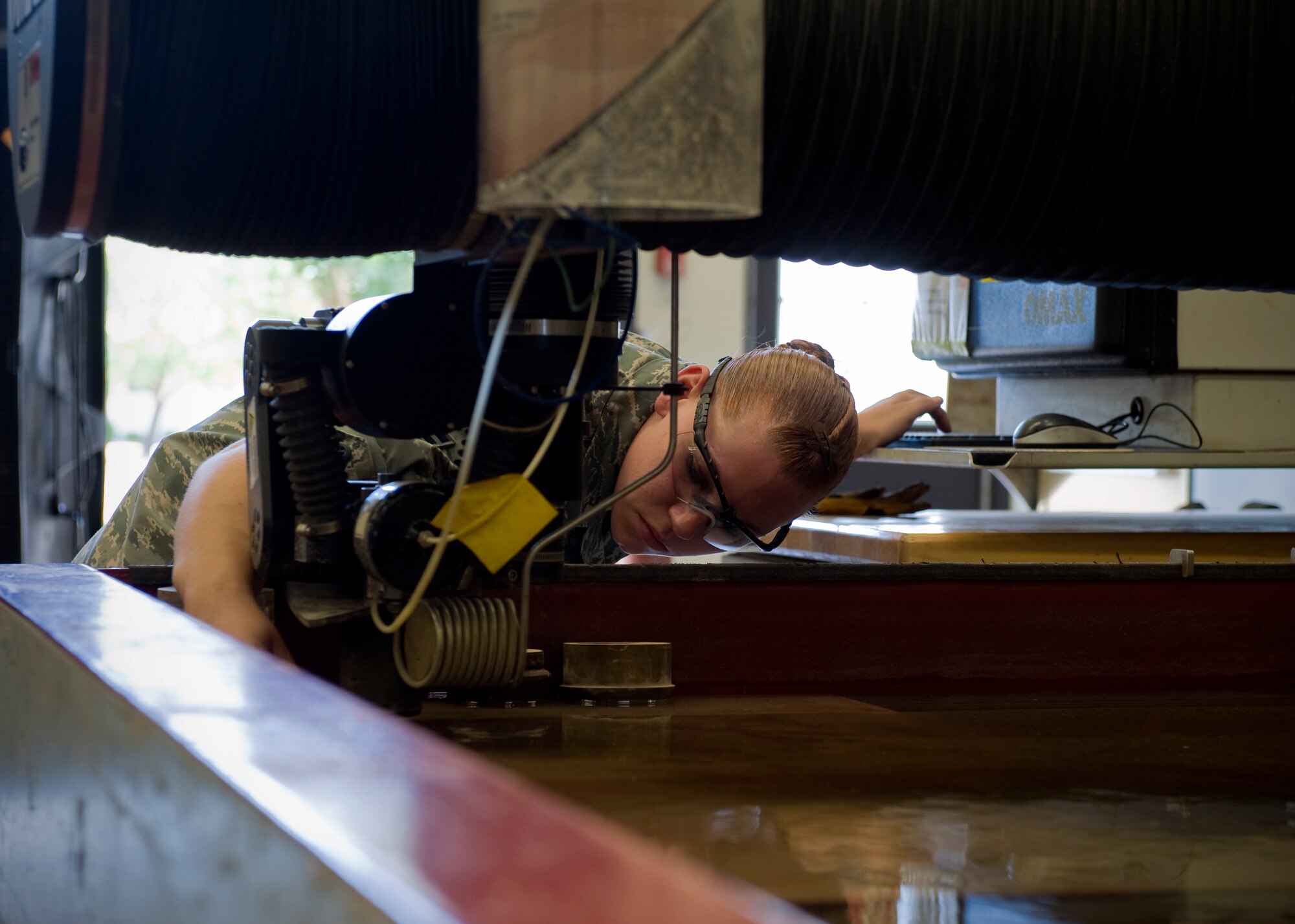 U.S. Air Force Airman 1st Class Brooke Goosen, 7th Equipment Maintenance Squadron, positions an abrasive nozzle onto a sheet of metal Aug. 14, 2012, at Dyess Air Force Base, Texas. The cut metal will be welded onto a Y-stand used to hold munitions. Goosen is the only female out of 28 Airmen in the Dyess metal shop and has more than seven years experience with welding. (U.S. Air Force photo by Airman 1st Class Jonathan Stefanko/ Released)