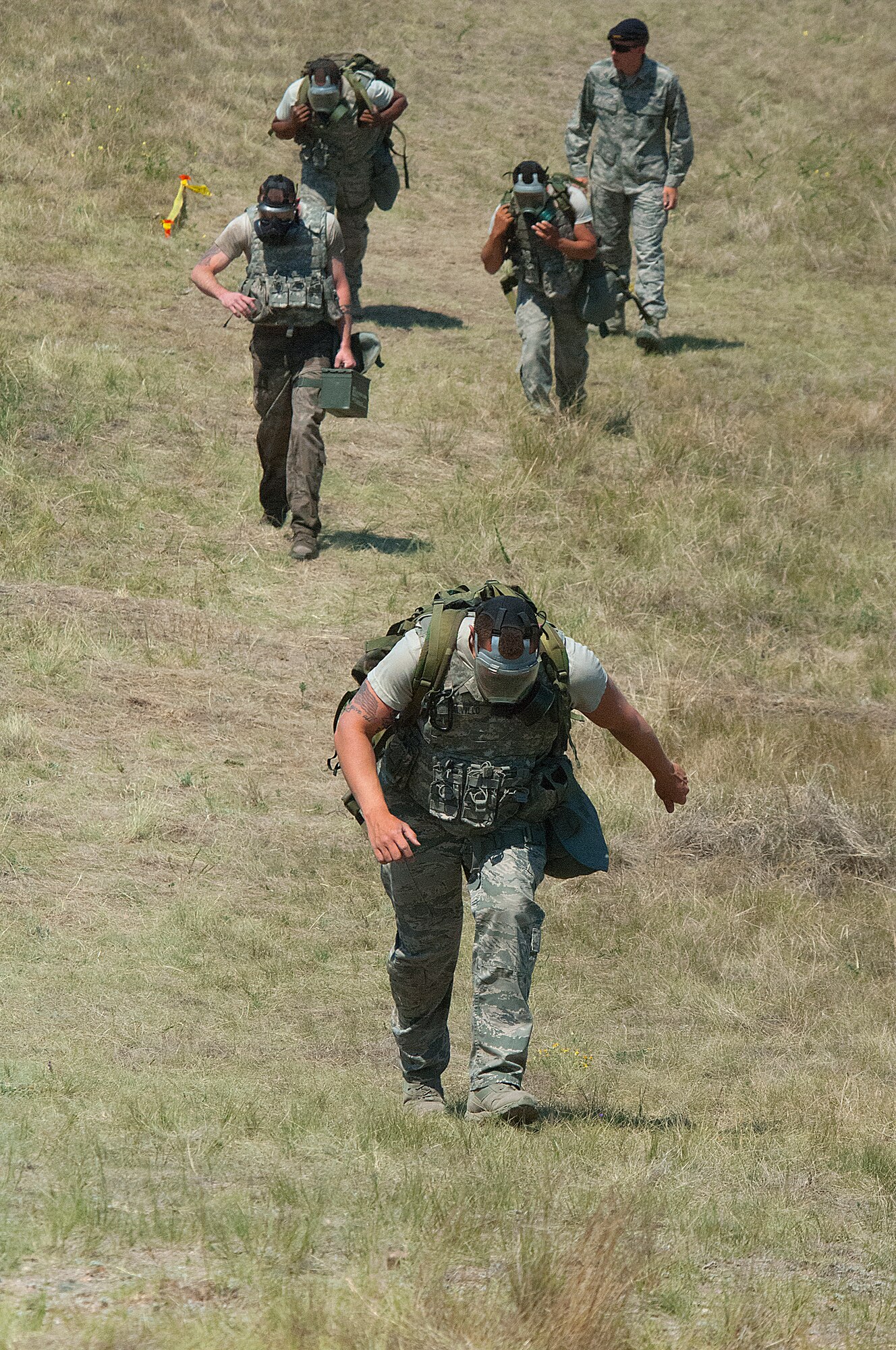 Airmen from the 790th Missile Security Forces Squadron climb a hill on F. E. Warren Air Force Base, Wyo., in gasmasks, and carrying heavy ruck sacks in the ruck-and-run portion of the Crow Creek Challenge Aug. 10. (U.S. Air Force photo by R.J. Oriez) 
