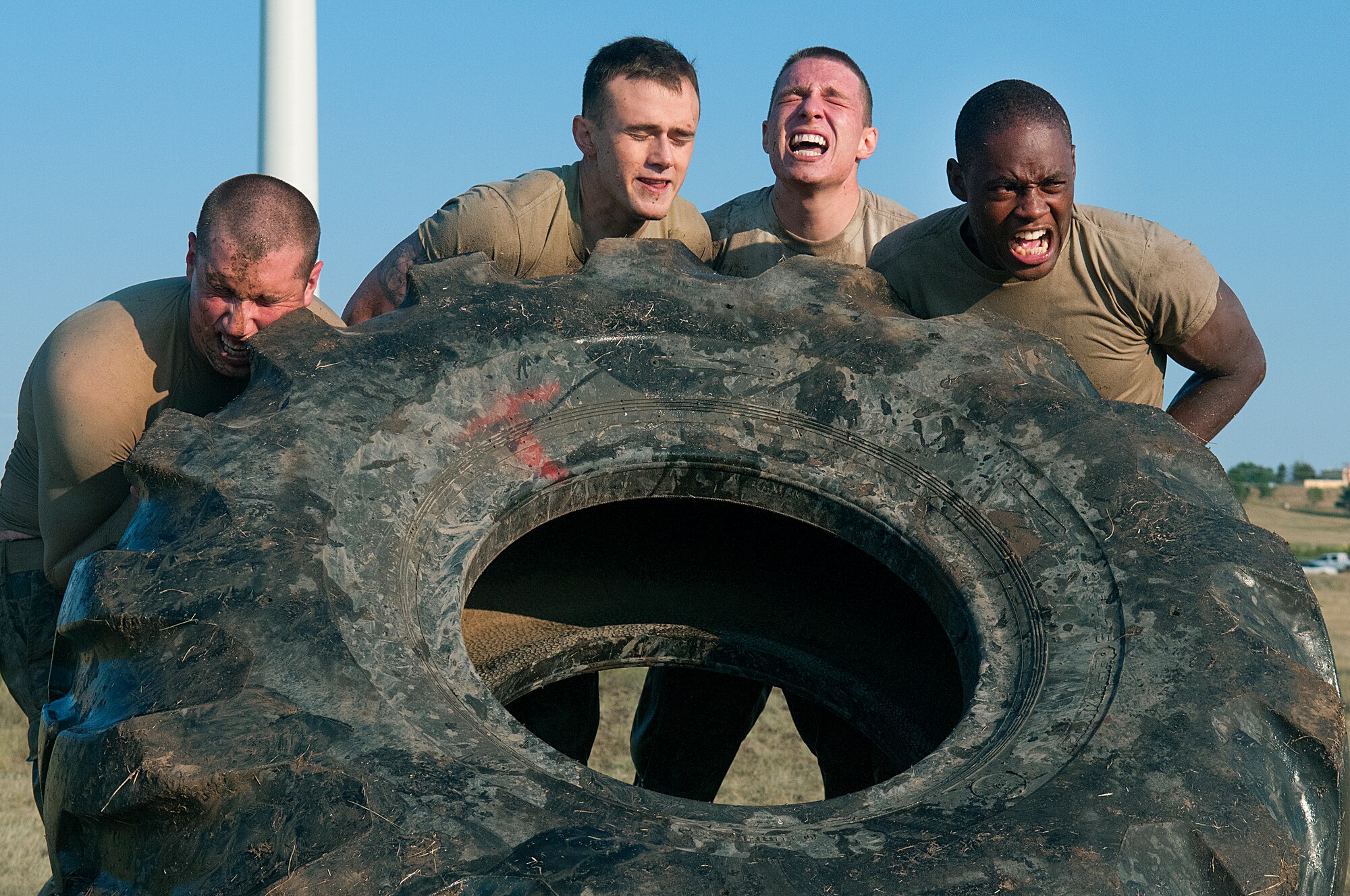 Senior Airman Robert McNabb, Airman 1st Class Phillip Rostek, Airman 1st Class Maxwell Schutte and Airman Jamal Stephen, all members of the 90th Security Force Squadron, struggle to flip a tractor tire, weighing approximately 350 pounds, during the Team Pain section of the Crow Creek Challenge Aug. 10. The 90th SFS team took part in the annual F. E. Warren Air Force Base, Wyo., competition, which challenges Airmen to the limits of their physical endurance and knowledge related to their job. (U.S. Air Force photo by R.J. Oriez)
