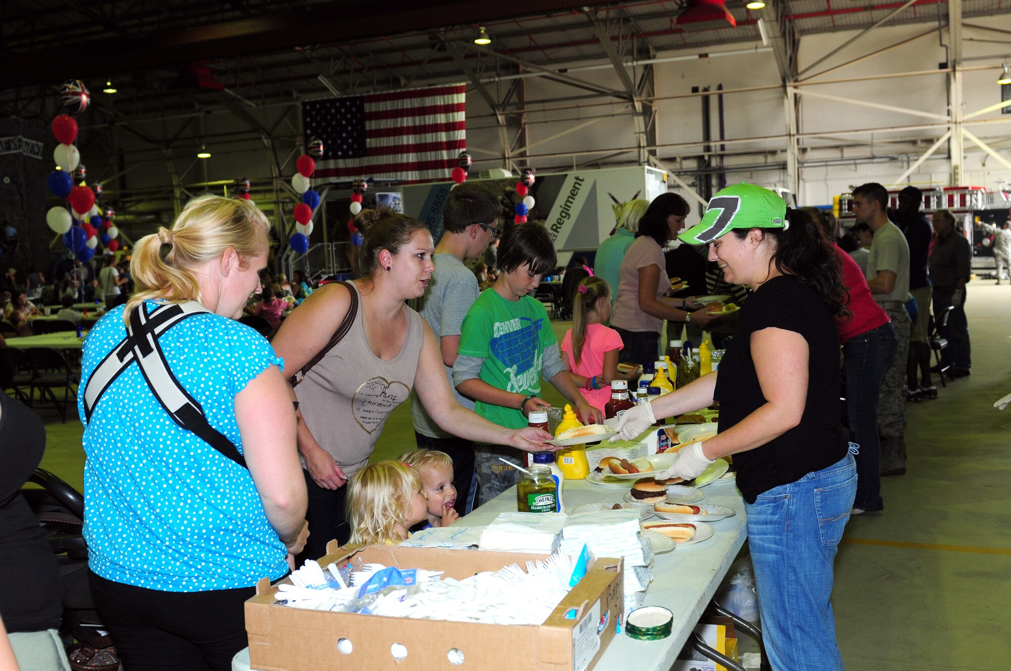 ROYAL AIR FORCE LAKENHEATH, England – Families of deployed servicemembers receive food during a joint deployed spouses’ luncheon Aug. 15, 2012. The luncheon featured a booth providing information about the F-15s stationed here, an area where children could try on chemical protective gear and the RAF also provided a rock climbing wall for children as well as a close combat virtual reality simulator.  (U.S. Air Force photo by Airman 1st Class Cory D. Payne) 