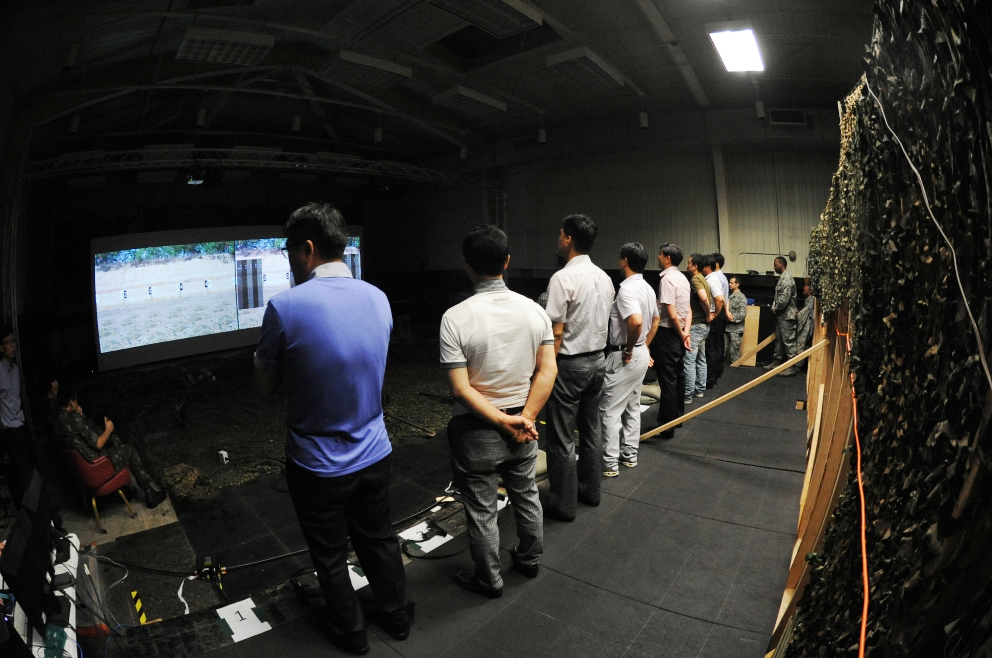 Members from the Gunsan City Police Department wait for final scores after firing an M9 handgun simulator weapon toward a digital screen on Kunsan Air Base, Republic of Korea, Aug. 10, 2012. Members from the GCPD were given a demonstration and tour of a firearms training simulator, which many defenders across the military use to train. (U.S. Air Force photo/Senior Airman Jessica Hines)