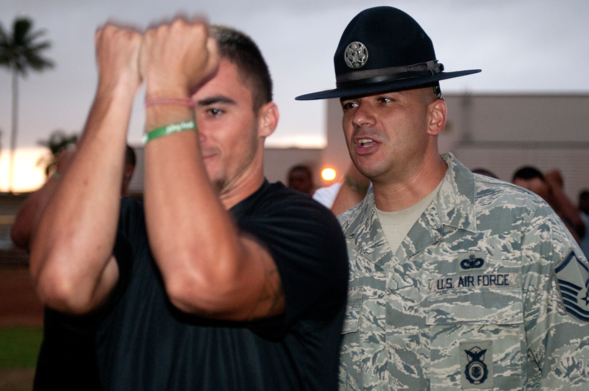 Master Sgt. John Mascolo, 647th Security Forces Squadron and former military training instructor, motivates a University of Hawaii football player during the physical training session after their 5 a.m. basic training style wake-up call Aug. 14 at Joint Base Pearl Harbor-Hickam. Air Force and Navy servicemembers took part in a team building exercise with the team for an early morning physical training session. The Warriors are scheduled to be on the road for their opener Sept. 1, in Los Angeles, against the University of Southern California Trojans. (U.S. Air Force photo/Staff Sgt. Mike Meares)